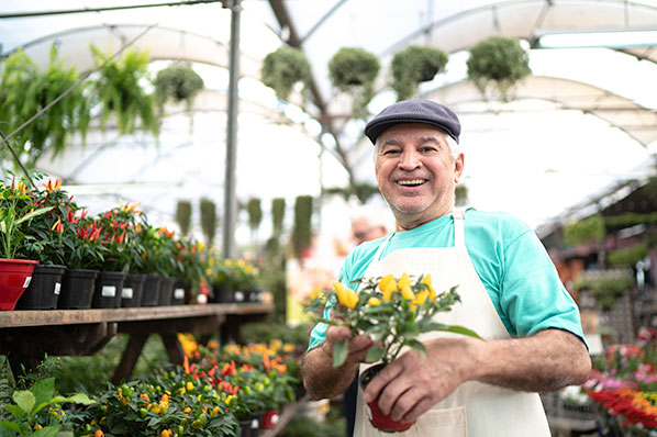 male nursery owner holding a pot of flowers