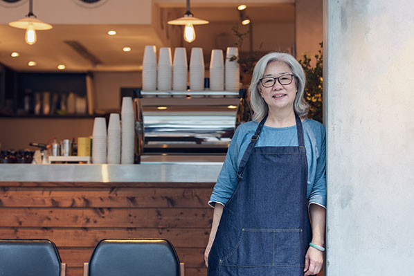 older female coffee shop owner in front of her shop