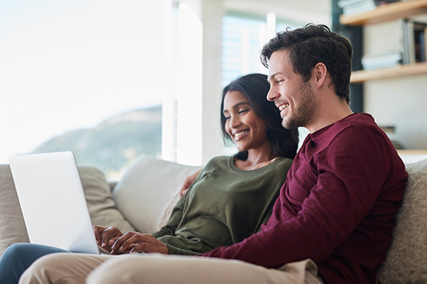 couple sitting on couch with laptop