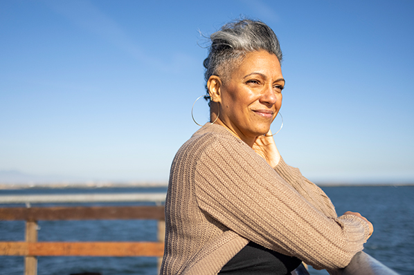 middle aged woman looking out onto the water from behind a ralining