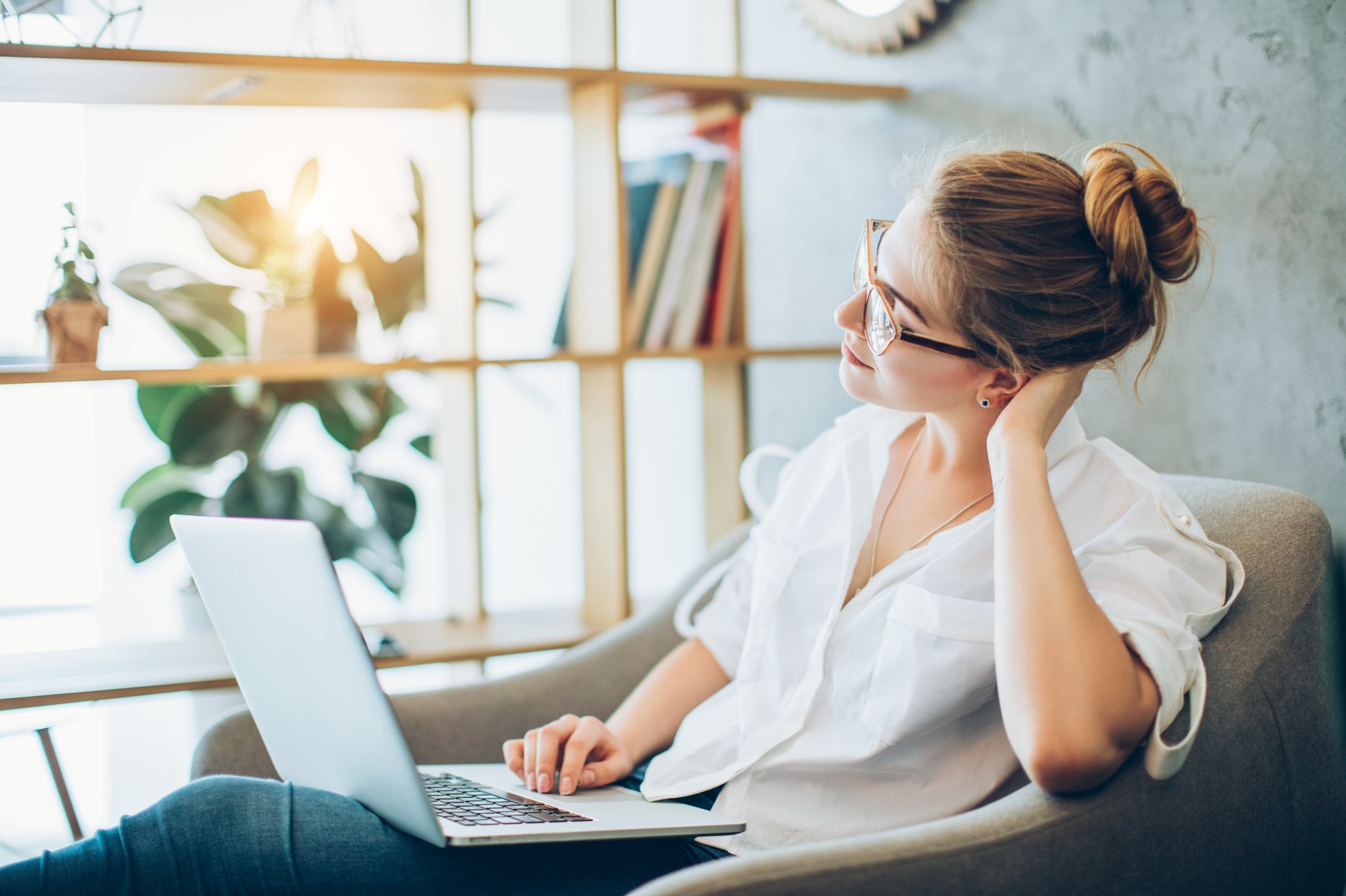 image of a white adult woman sitting in an archair looking at her laptop