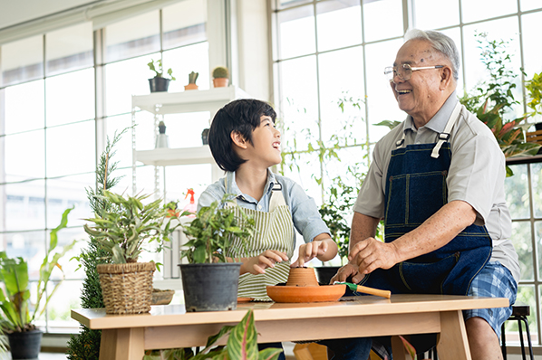 Older male with a young grandson laughing while re-potting house plants.