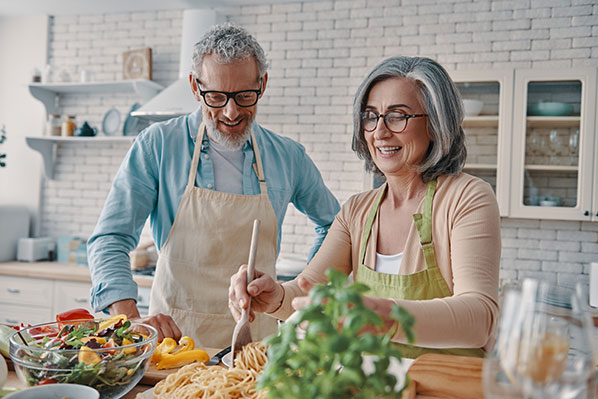 older couple cooking at home in their kitchen having fun