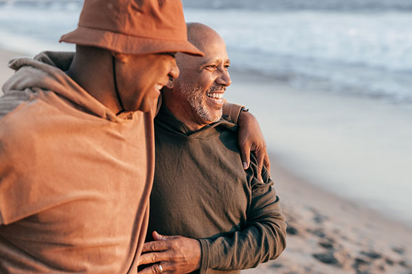 middle aged male couple hugging and walking on the beach