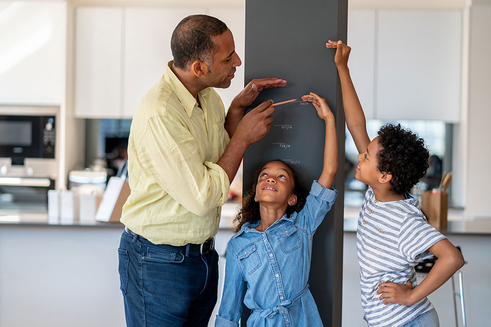 dad marking the height of his kids on a kitchen wall