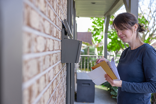 woman looking through the mail she just picked up from the mailbox