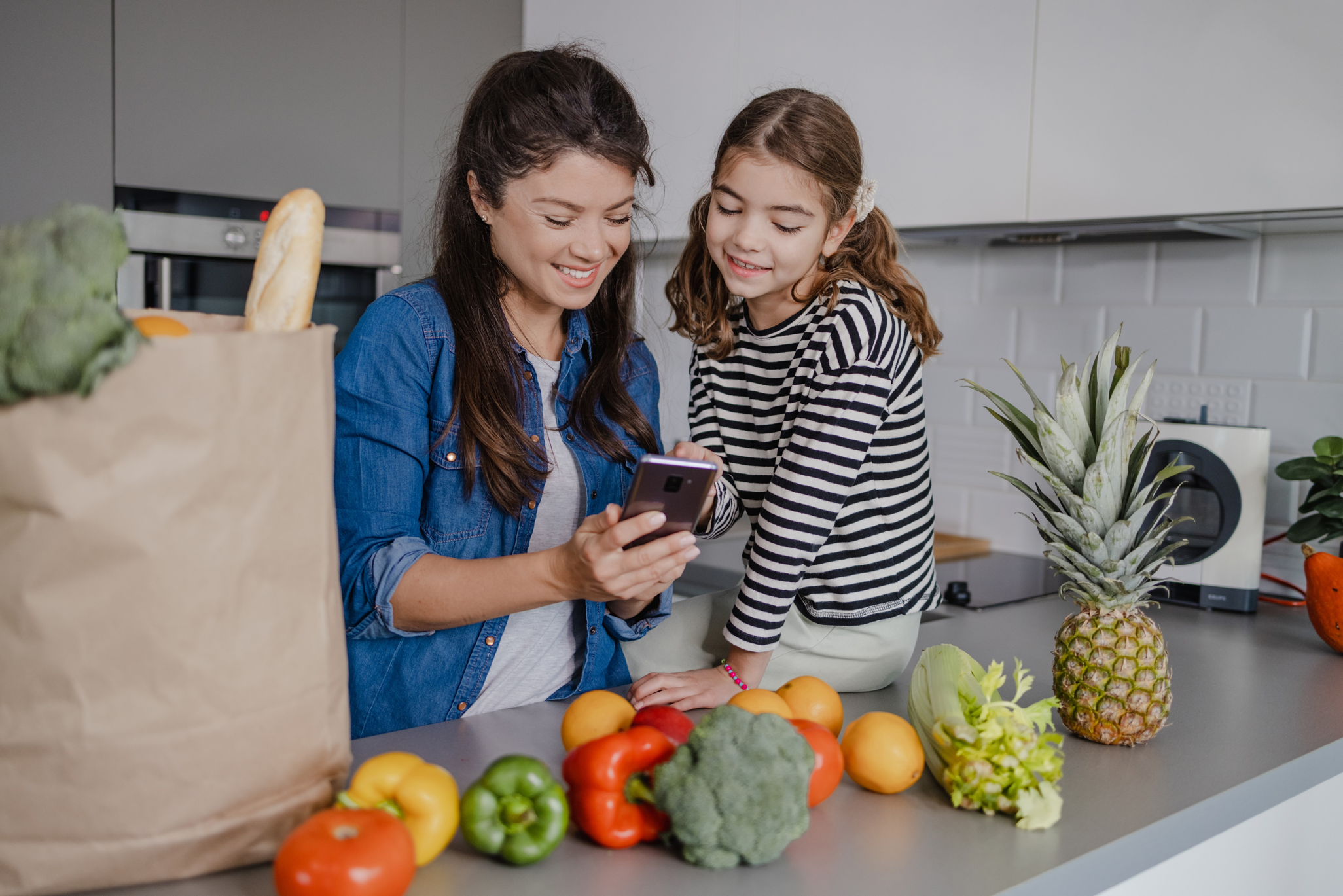 mom and daughter putting groceries away