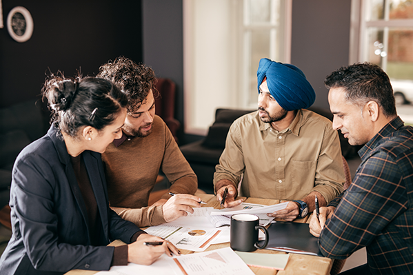 Clients meet with two advisors and they discuss their finances over coffee.