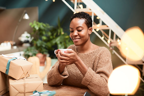black woman with short hair enjoying a cup of tea wrapping presents 