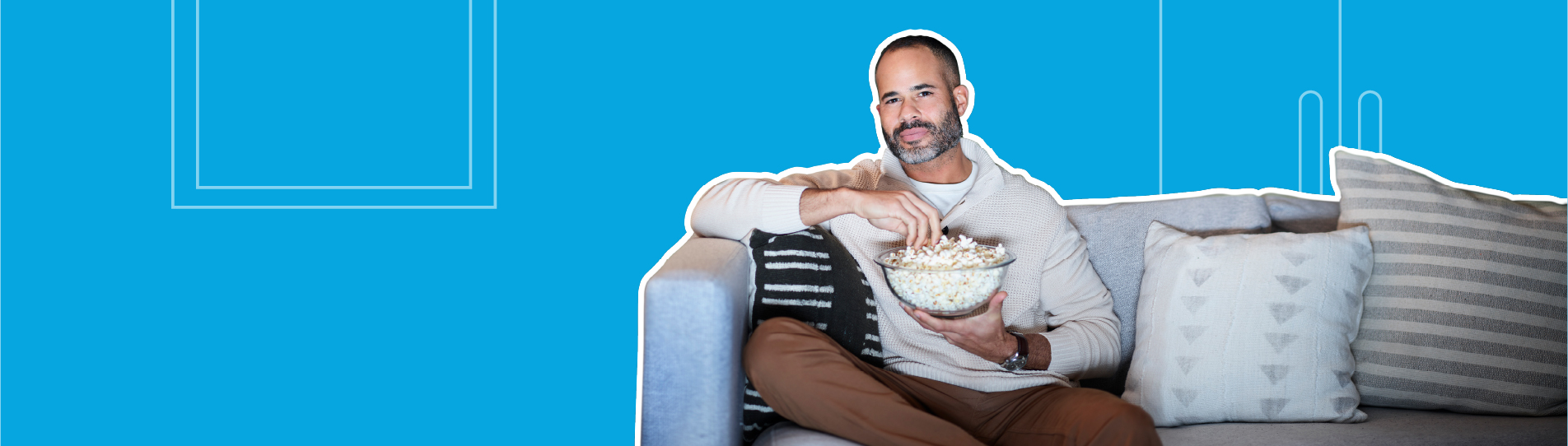 man sitting on couch holding a bowl of popcorn and watching TV