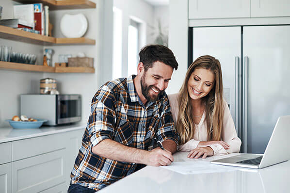 young couple sitting at kitchen island looking at their finances