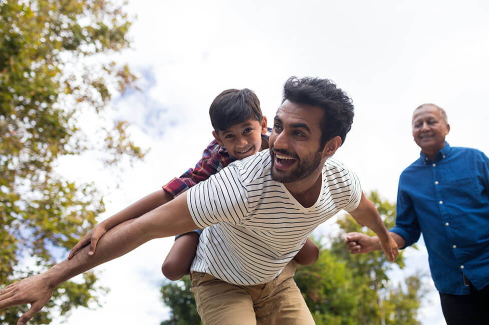 young son on his dad's back pretending to fly