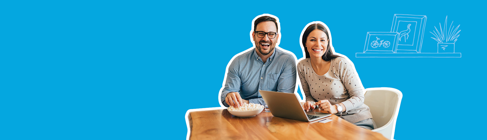 smiling couple sitting at the table looking at their laptop