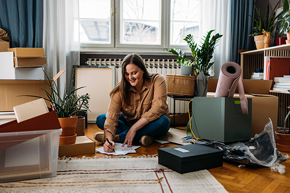 girl sitting on floor smiling with moving boxes